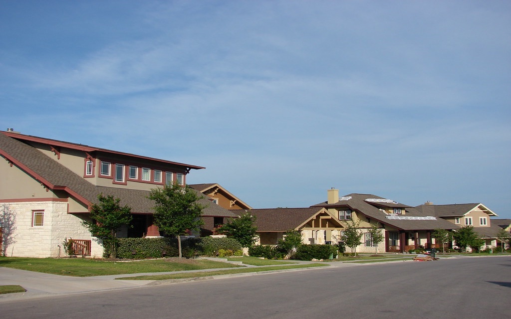 A residential street of new limestone and render homes in Cedar Park, Texas